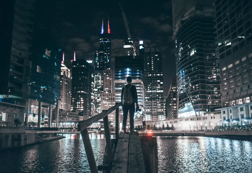 Photography - a man gazes out at a dockland/riverside modern development. Downloaded from Wallhaven. Author and rights unknown - please get in touch for crediting, or if there's any issue.